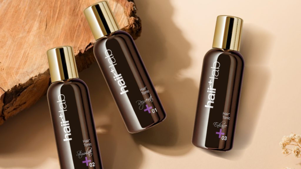 Hair tonic and hair loss tonic dropper bottles side by side on a bathroom counter for comparison